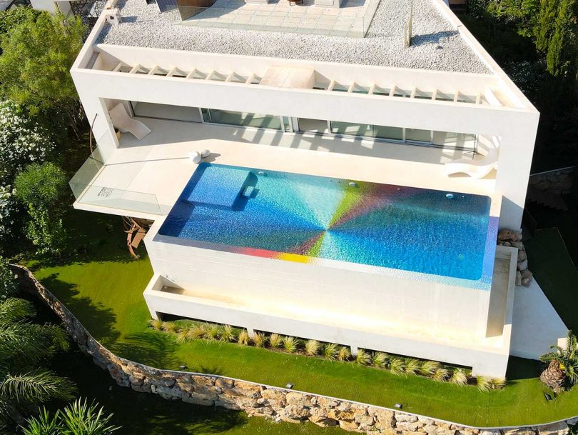 aerial view looking down onto top of modern house with a rectangular colorful pool