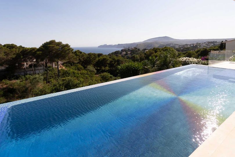 angled view looking over a colorful swimming pool with greenery in distance