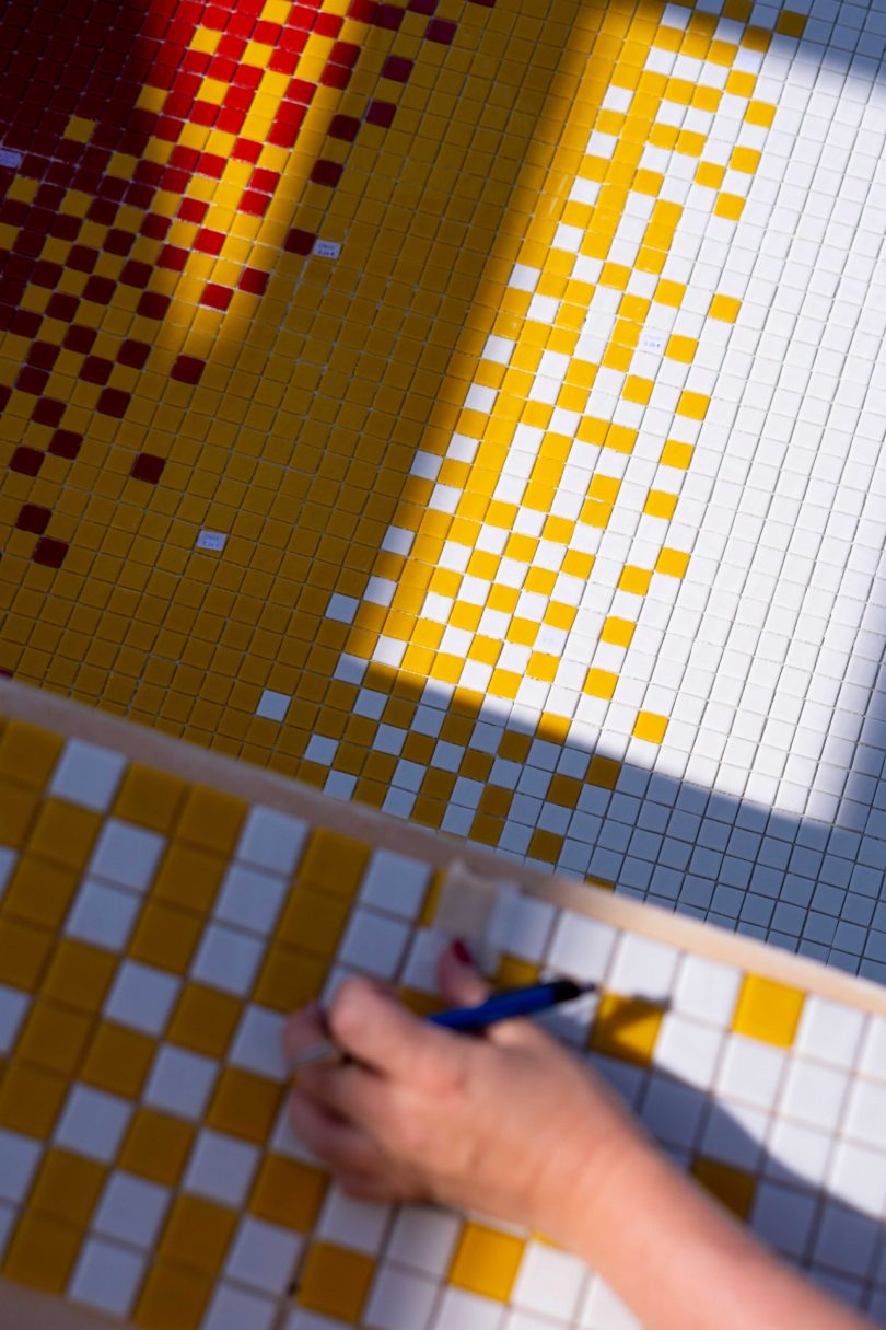 looking down into empty swimming pool with colorful mosaic tile being laid