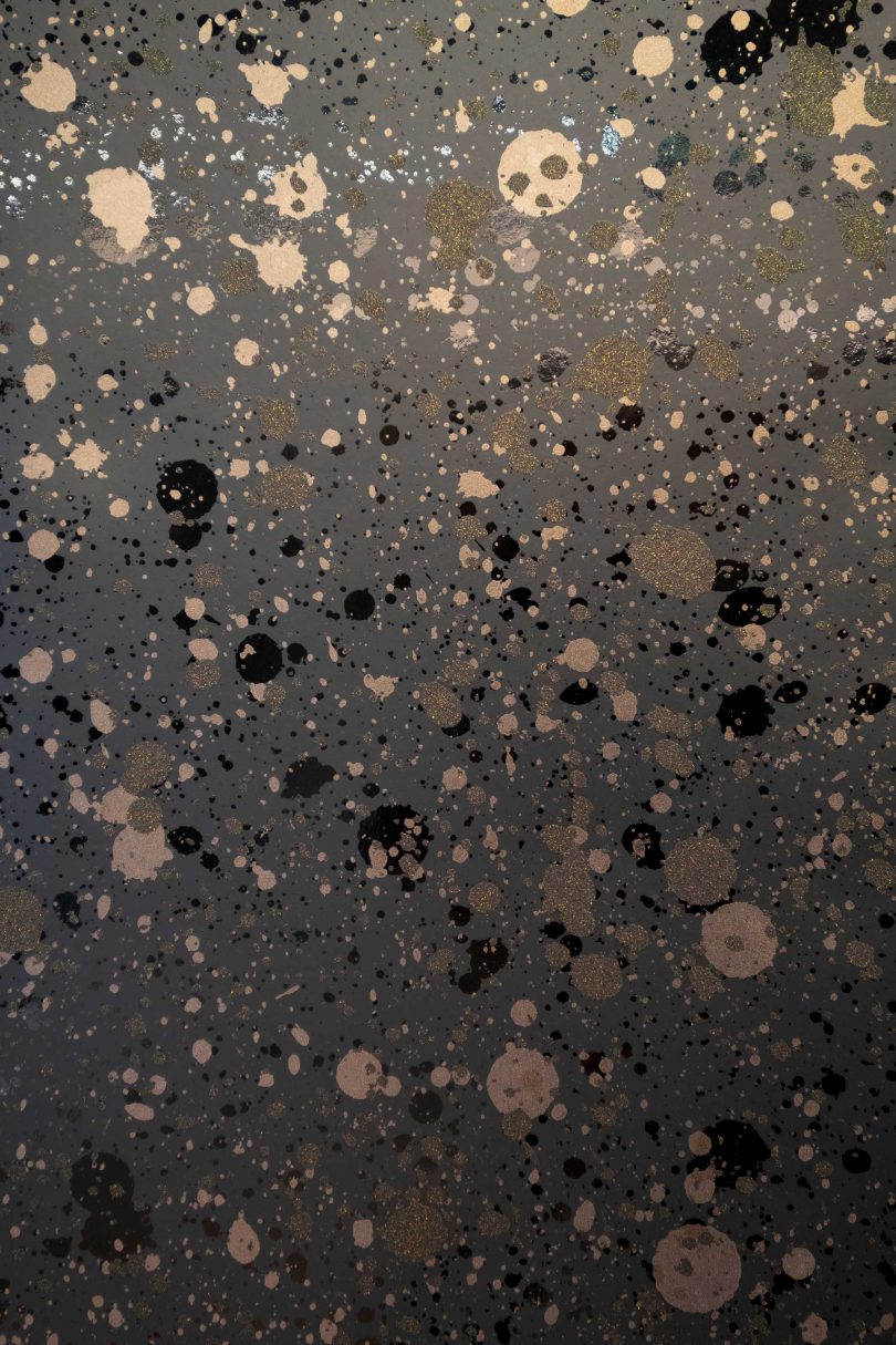 closeup of wallpaper design of metallic splattered design in black mylar