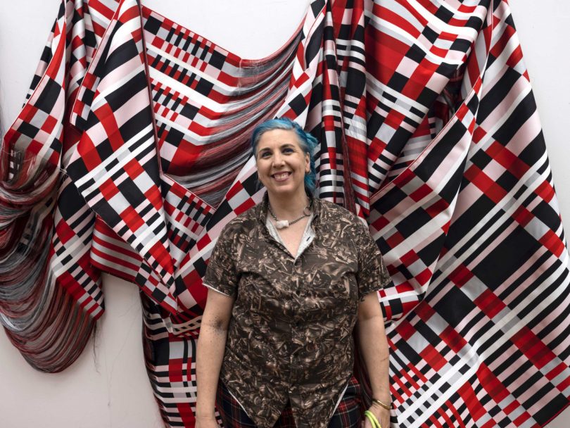 Artist Liz Collins standing in front of artwork that inspired new wallpaper collection