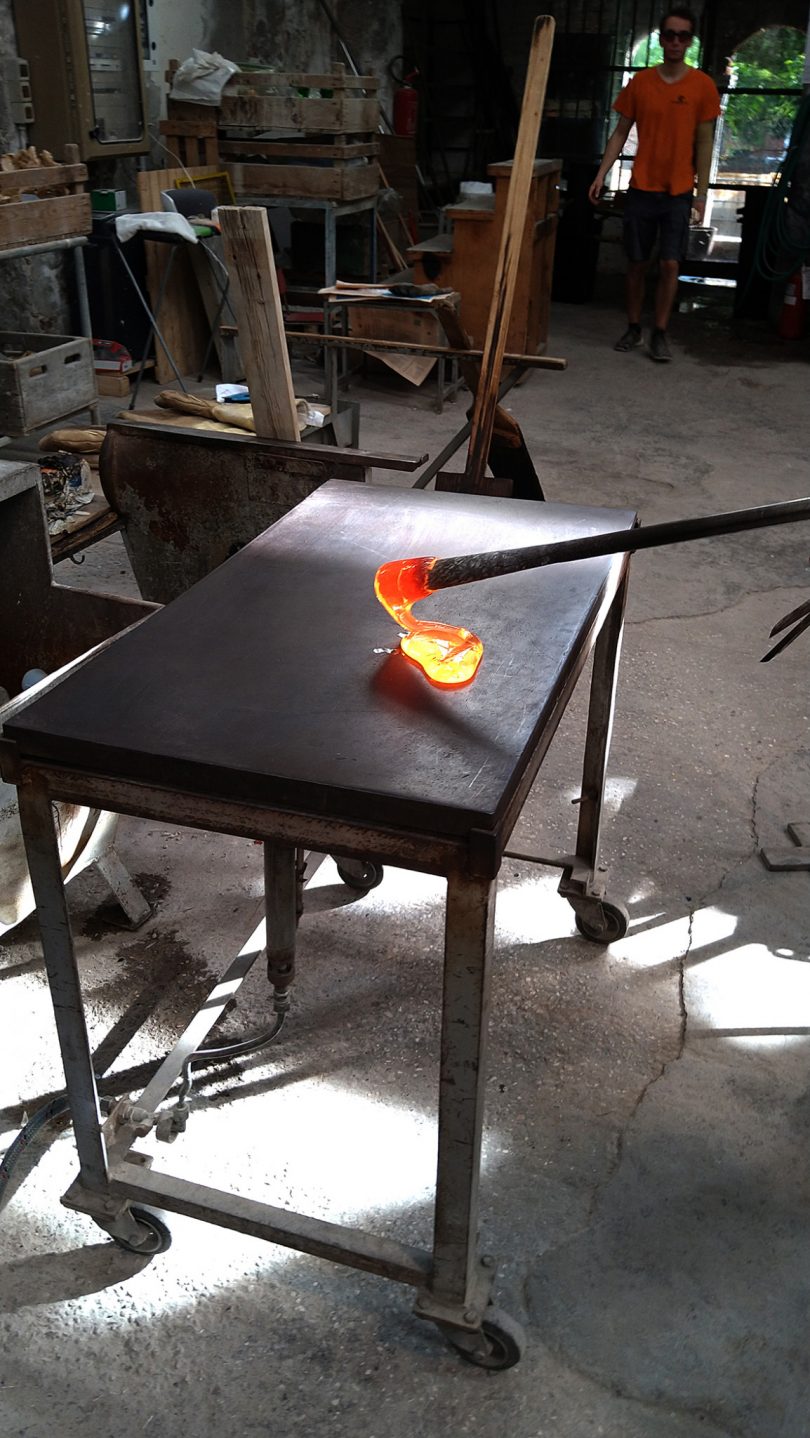 hot blob of molten glass being placed on black work table