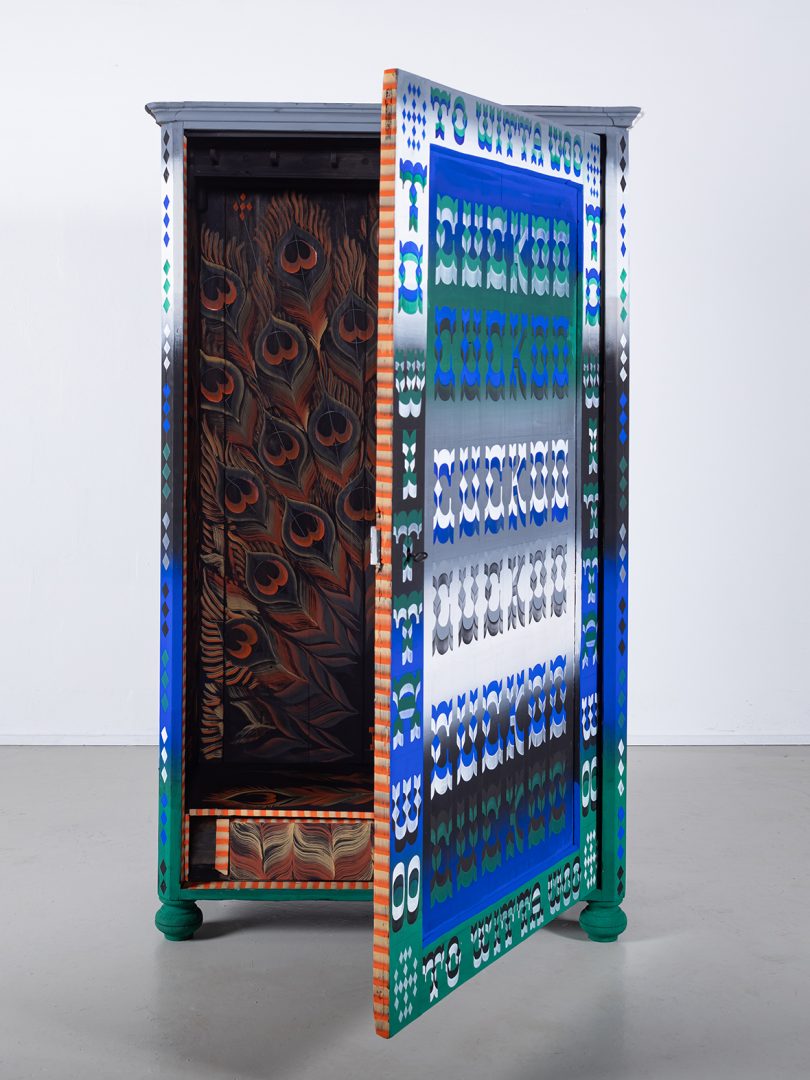 blue, green, grey, and black patterned cabinet with door open in exhibit space