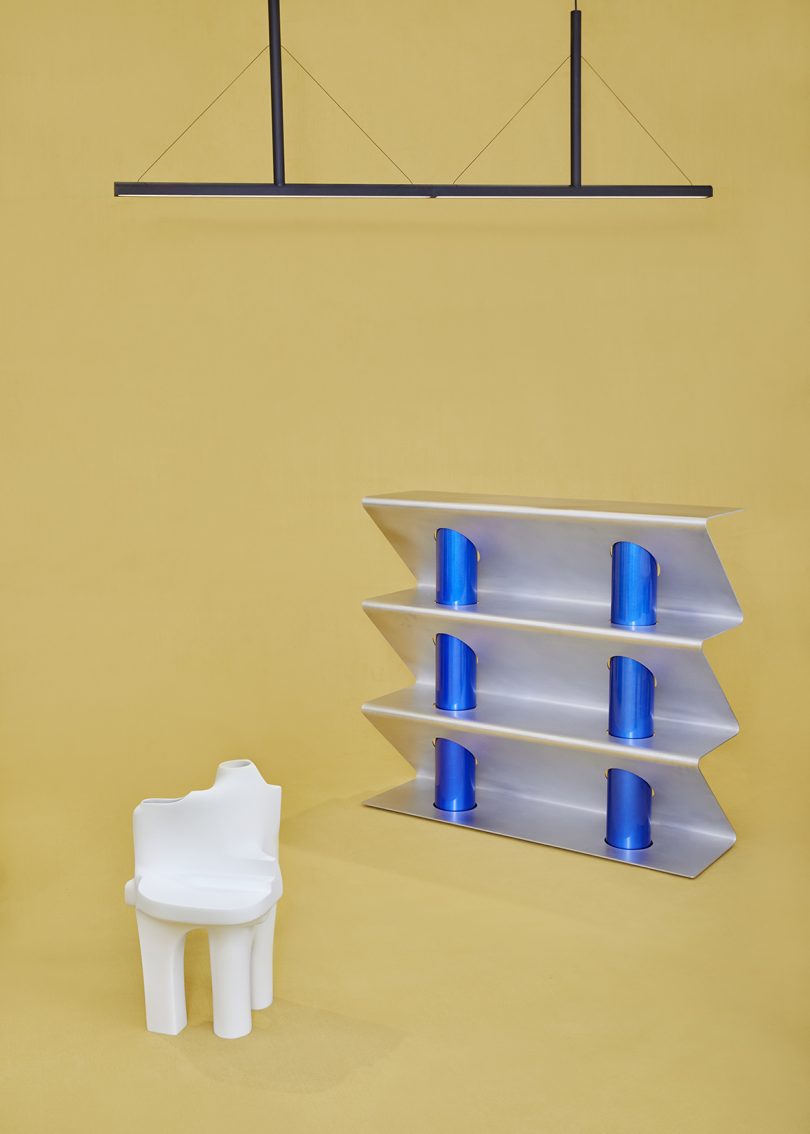 white sculpture, shelving, and lighting on butter yellow background