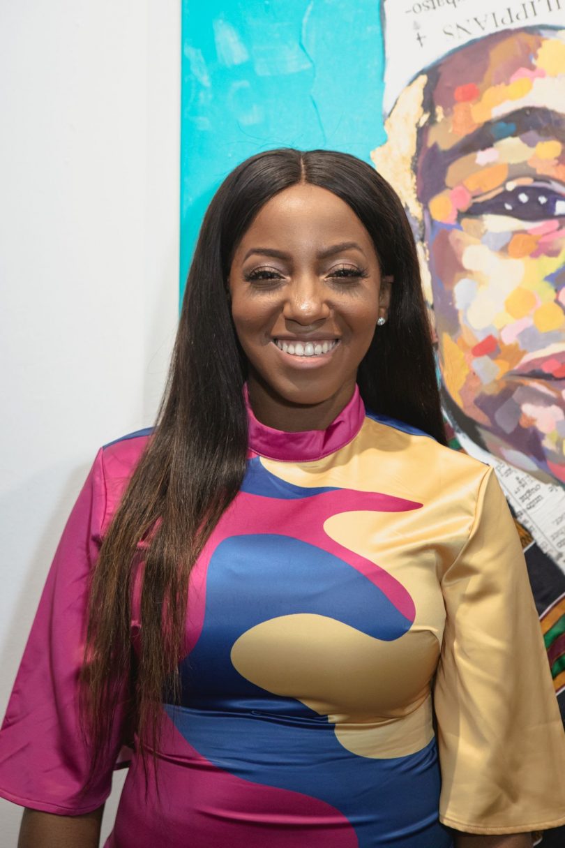 dark-skinned woman with long black hair wearing an abstract, colorful top