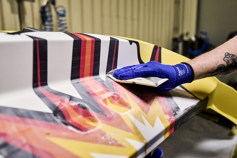 hand in blue glove polishing car exterior