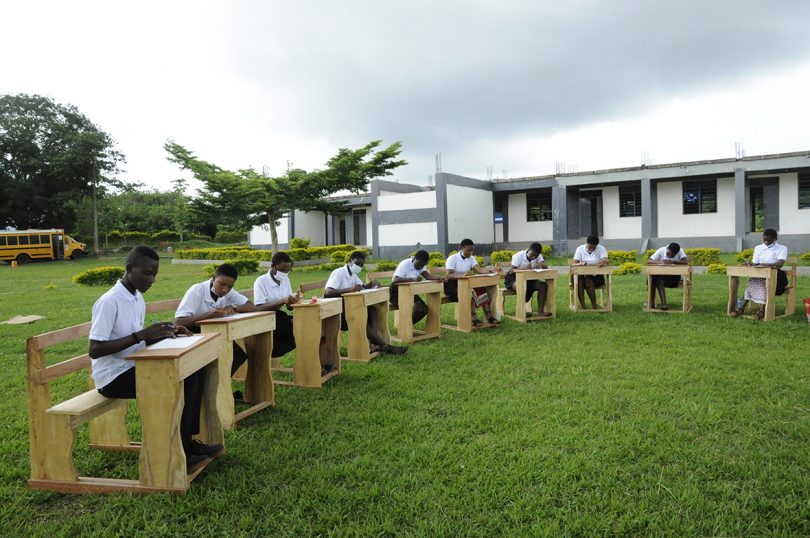 group of schoolgirls seated in wooden desks outdoors