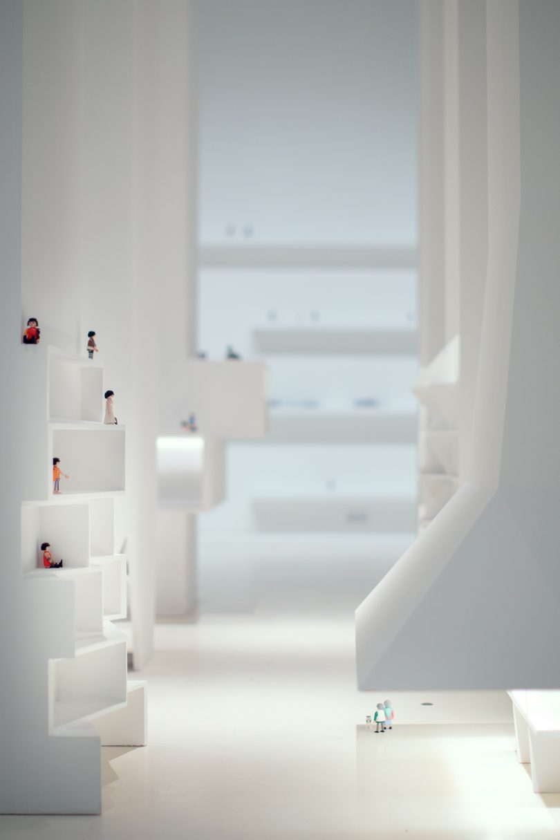 inside interactive exhibition with all white surfaces and small figurines representing people