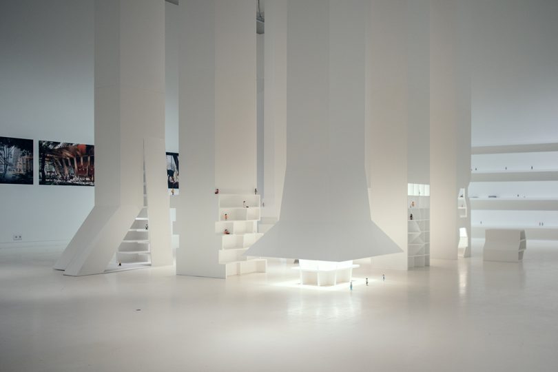 inside interactive exhibition with all white surfaces and small figurines representing people