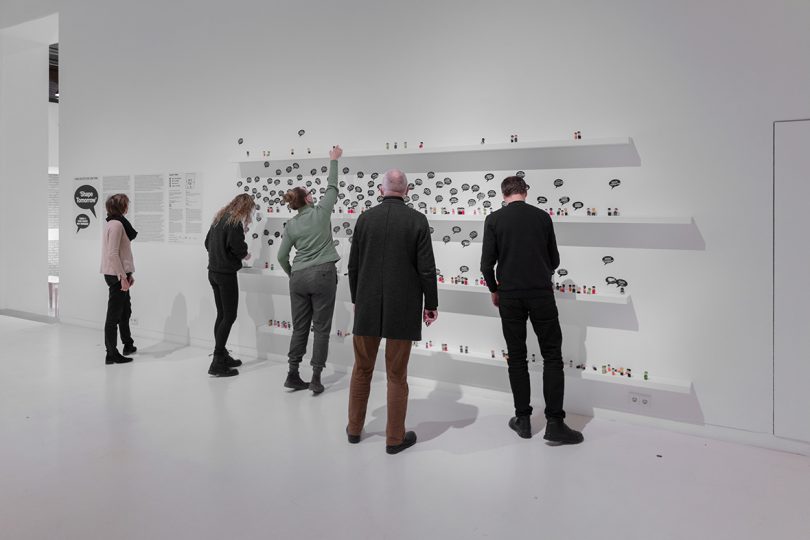 visitors inside interactive exhibition with all white surfaces and small figurines representing people