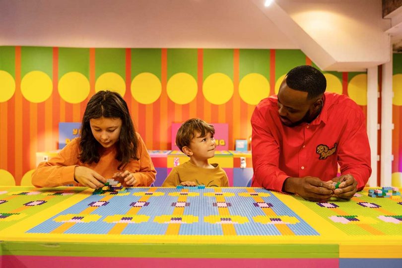 designer Yinka Ilori talking to two children playing with LEGO bricks