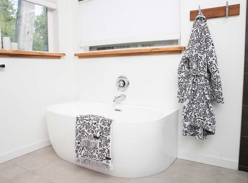 white bathroom with towel and robe featuring artwork by keith haring