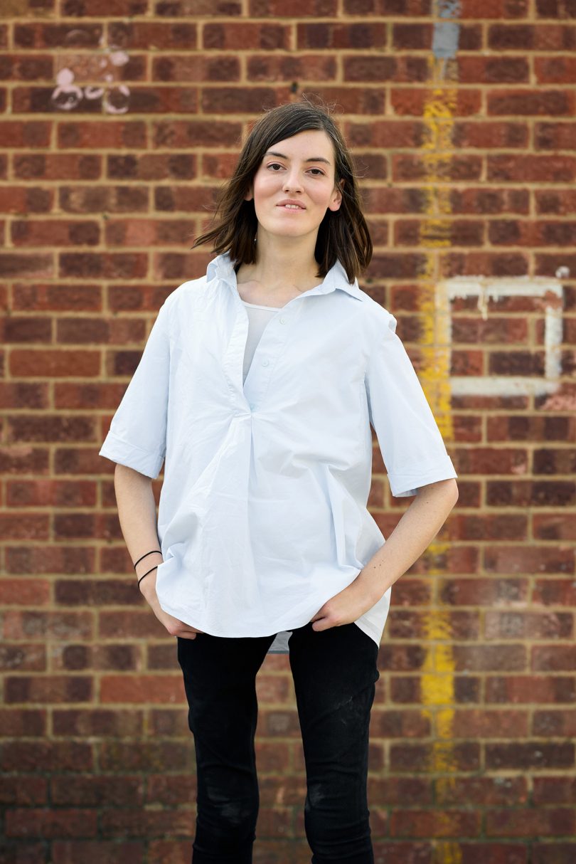 light skinned woman with dark hair wearing white short sleeved shirt and black pants