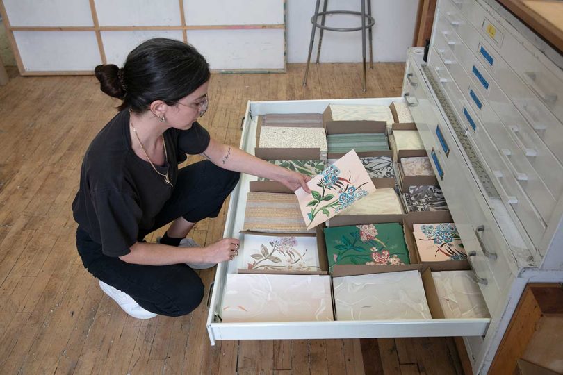 artist viewing wallpaper samples from a drawer