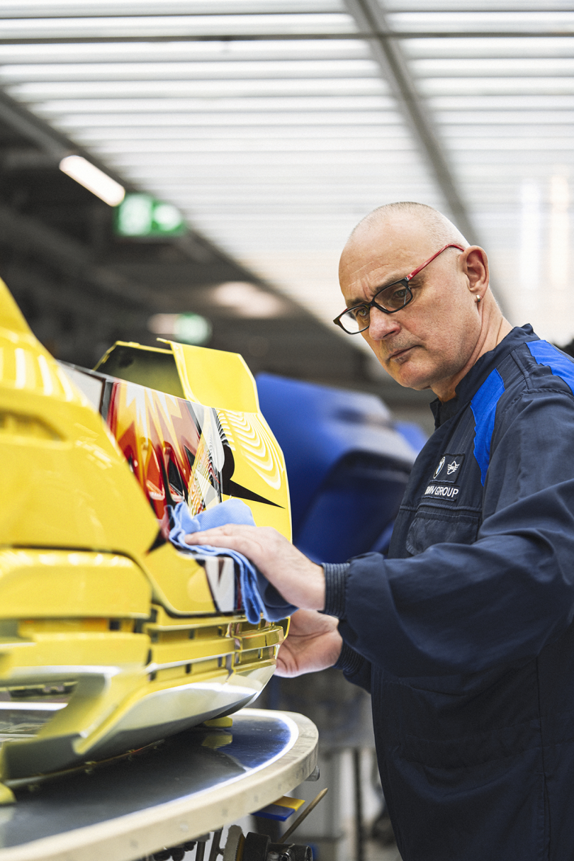 light-skinned bald man buffing a piece of car exterior