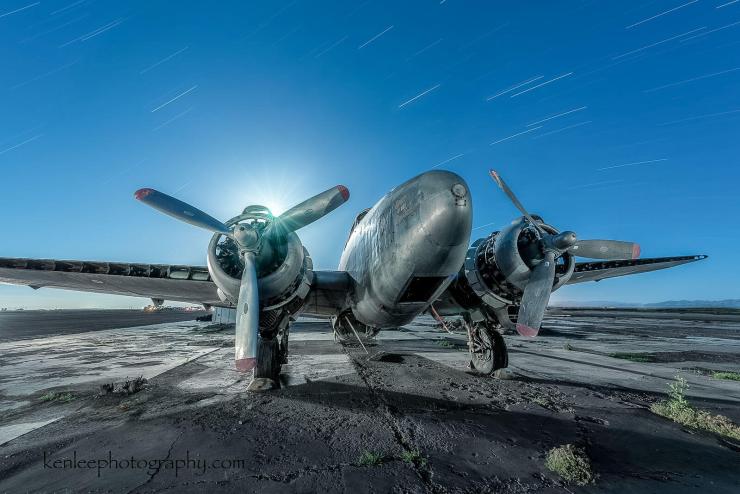This photo of a defunct airplane has 33-minute star trails "stacked" and a full moon peaking over the propeller.