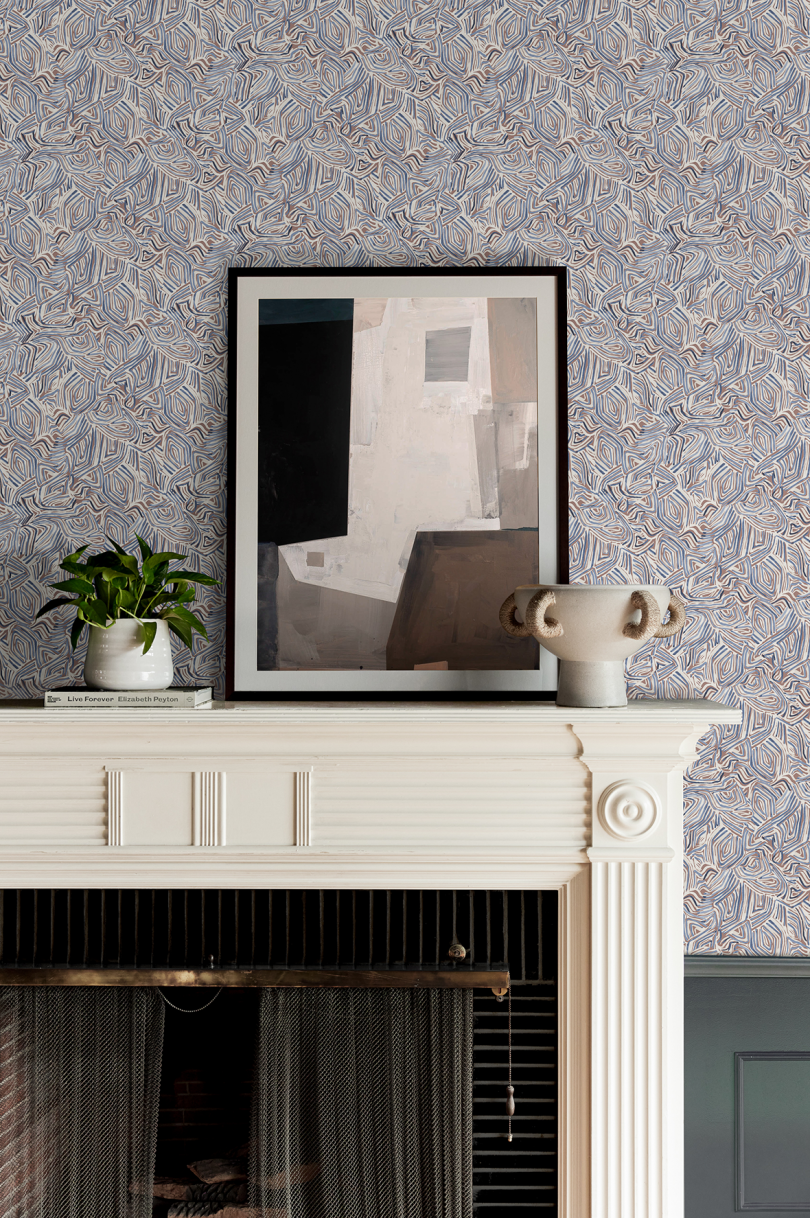 blue and grey patterned wallpaper with mantel and artwork