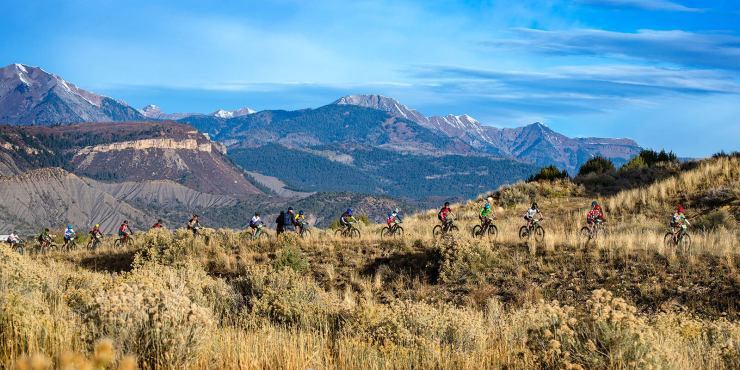 Mountain bike riders in a line with mountains as a backdrop