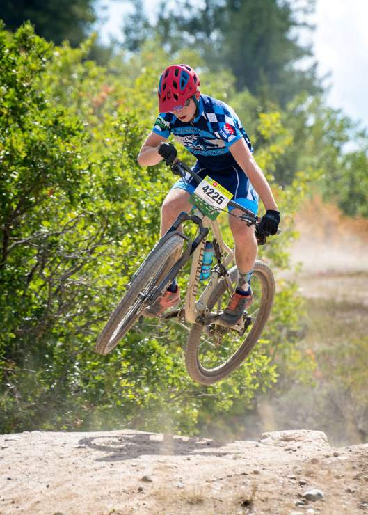 mountain bike racer in mid air jumping a dirt hill