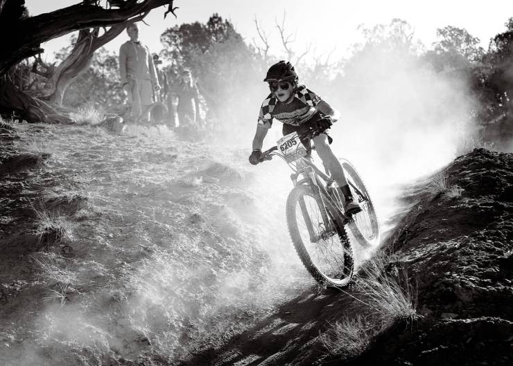 mountain bike rider with dust from wheels in black and white
