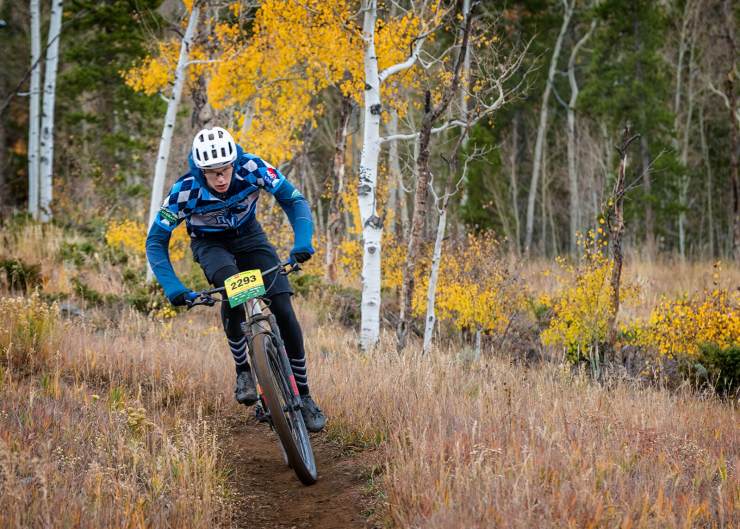 Rider coming around corner with yellow aspen leaves and trees as backdrop