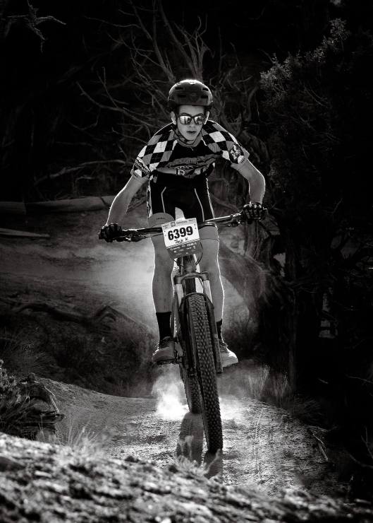 mountain bike rider with dust from wheel and the light light up behind them