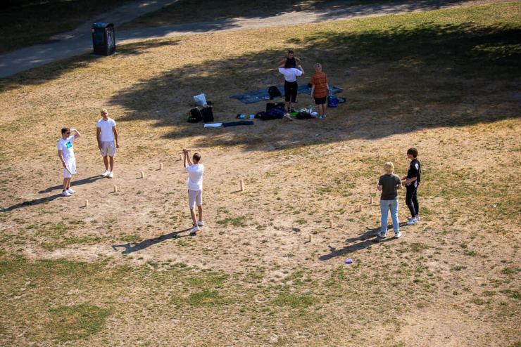 people playing Kubb in grassy area near Regensburg bridge