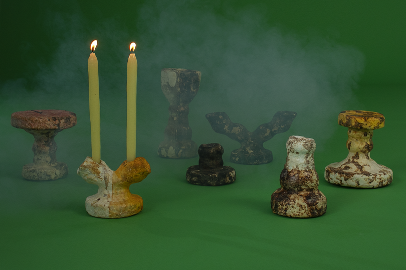 collection of vessels with two lit candles on dark green background with white smoke